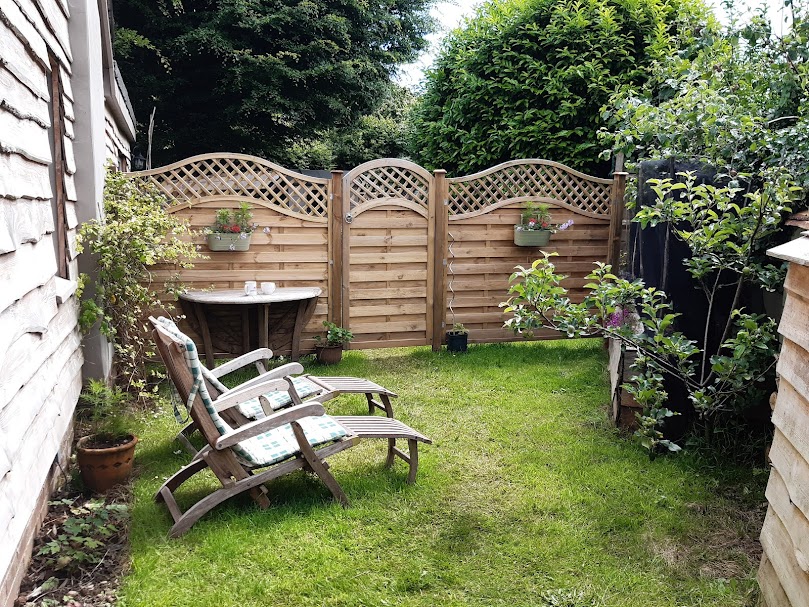 Private garden with 2 wooden steamer chairs, table and chairs.